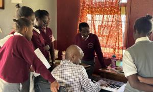 Greg Satterthwaite demonstrating on a keyboard for a group of students at the Moi Girls School.