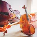 A Double bass, cello, and a violin lying on the floor with a bright background