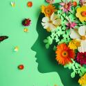 Silhouette of a face with flowers and butterflies in and around the mind. Light green background.