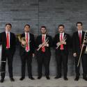 The Bulldog Brass Society standing in front of a gray brick wall